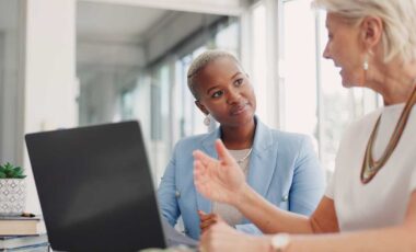 women sitting at computer and talking