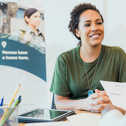 The mid adult female soldier smiles at an unrecognizable male banker.