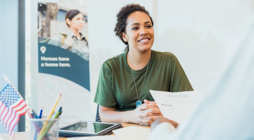 woman veteran smiling at desk speaking with other person